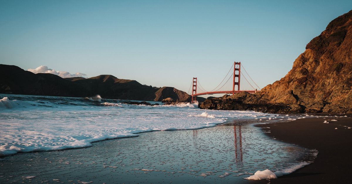 View of the Golden Gate Bridge from a scenic beach at sunset in San Francisco, California.